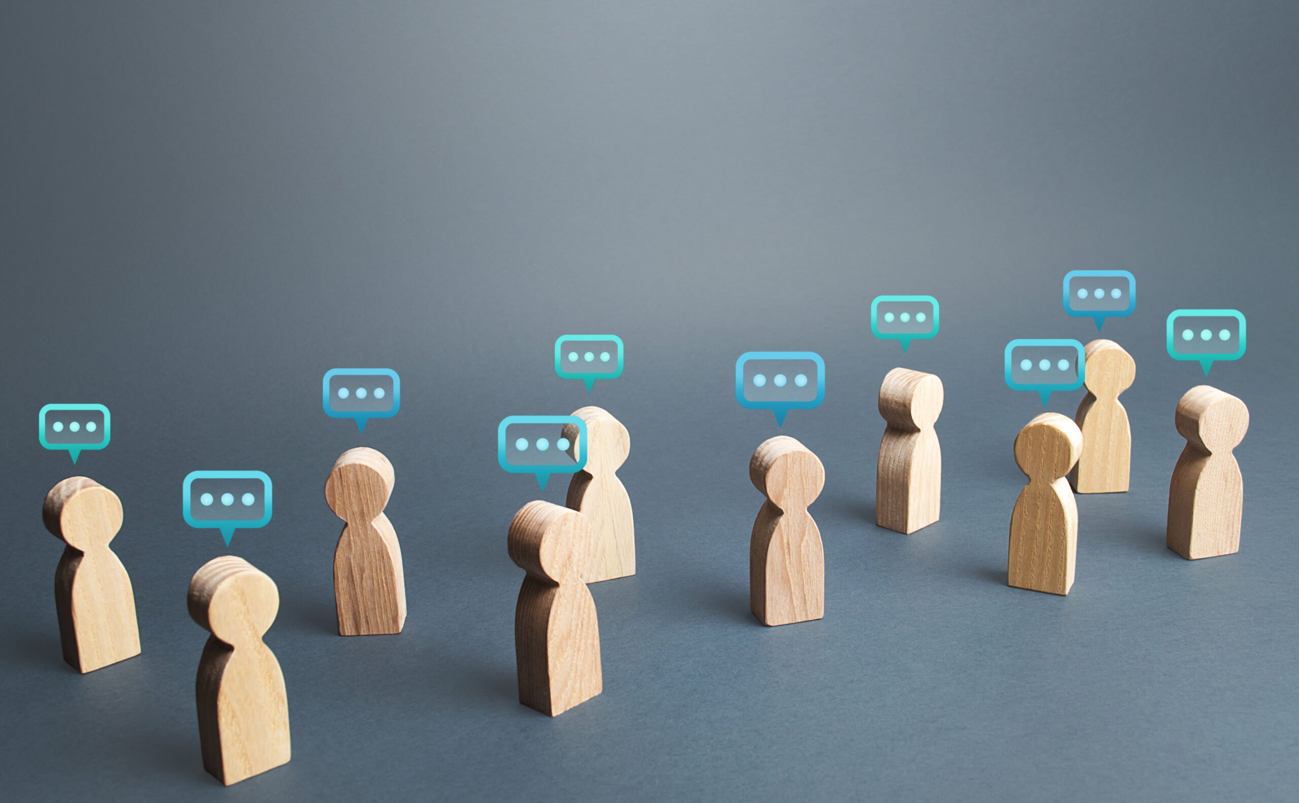 A group of wooden figures with transparent blue comment bubbles above their heads.